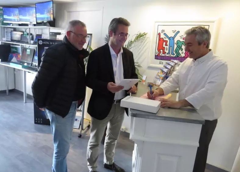 Trois professionnels discutant devant un comptoir de services informatiques.